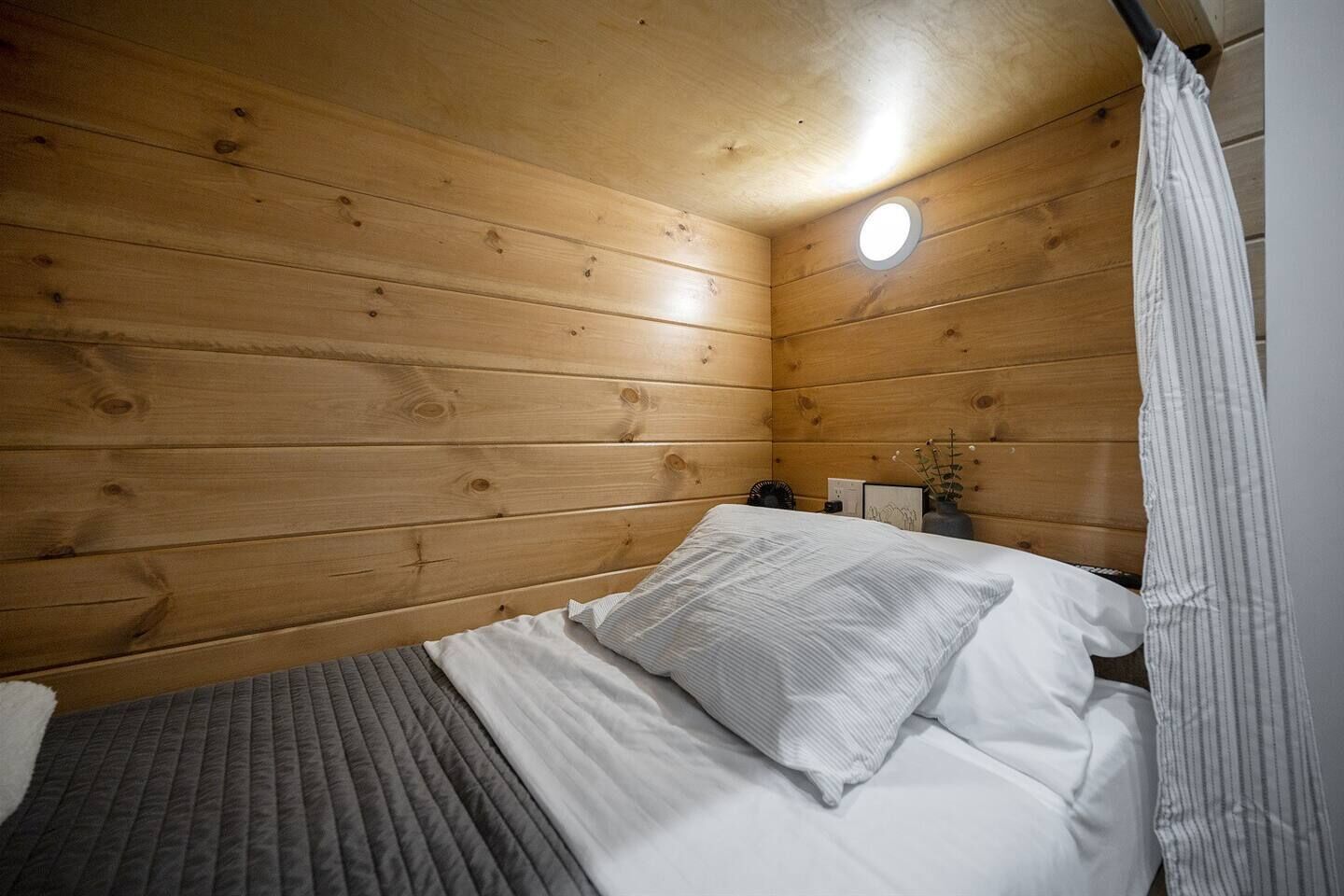 Une pièce de style cabane en bois, avec un lit, une petite table et une table de chevet.
