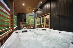 Ein Whirlpool mit Holzterrasse, Deckenventilator und Glastür zum Essbereich.
