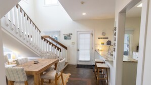 Ein Essbereich mit Holztisch und -stühlen, eine Treppe und eine Küche mit Arbeitsplatte und Spüle.