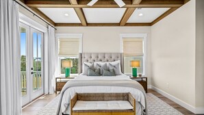 Een slaapkamer met een groot bed, twee nachtkastjes, een bankje en uitzicht op de omgeving.