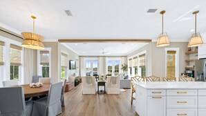 Een ruime keuken met een centraal eiland, grote ramen en moderne hanglampen.