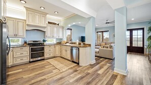 A spacious kitchen with wooden flooring, built-in cabinets, and a large island.