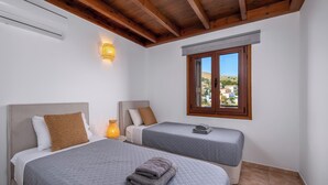Ein Schlafzimmer mit zwei Betten, einem Fenster mit Blick, einer Wand-Klimaanlage und einer Wandleuchte.