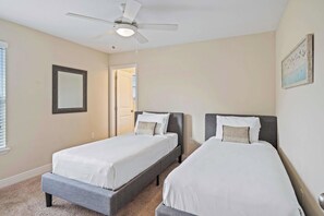 A bedroom with two beds, a ceiling fan, a door, and a framed picture on the wall. - Solterra 6BR Pool Home w Spa & Game Room near WDW (Davenport)