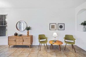 A room with a wooden cabinet, two green chairs, a round table, a floor lamp, and two framed pictures on the wall. - Solterra 6BR Pool Home w Spa & Game Room near WDW (Davenport)