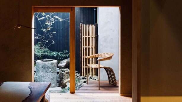 Ein traditionelles japanisches Interieur mit Tatami-Böden, einem Bambus-Raumteiler und einem hölzernen Stuhl.