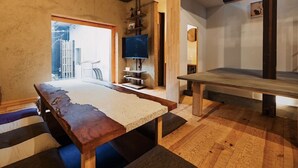 Ein modernes Zimmer mit einem großen Holztisch, einem Fernseher und Blick ins Freie.