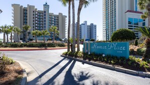 A hotel entrance with a sign reading "Ramon Place 24038" surrounded by palm trees and modern buildings. - RP306 -  OMG This View! XL Corner Balcony! Indoor & Outdoor Pools! WOW! (Orange Beach)