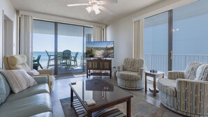 A spacious living room with a sofa, armchairs, a coffee table, and a TV. There is a balcony with a view of the ocean. - RP306 -  OMG This View! XL Corner Balcony! Indoor & Outdoor Pools! WOW! (Orange Beach)