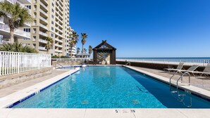 A swimming pool with a wooden gazebo, palm trees, and a high-rise building in the background. - RP306 -  OMG This View! XL Corner Balcony! Indoor & Outdoor Pools! WOW! (Orange Beach)