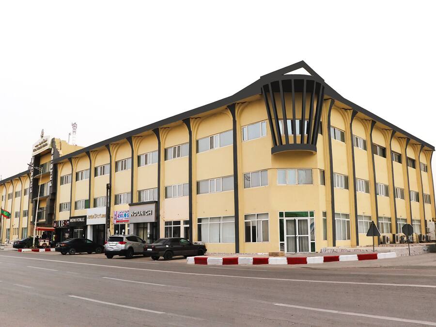 A multi-story hotel with a yellow facade, multiple windows, and a prominent entrance.