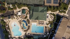 An aerial view of a hotel with a swimming pool, tennis courts, and a covered area.