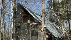 A rustic cabin with a sloped roof, wooden walls, and a window. - Streeter Mountain Farm (Rumney)