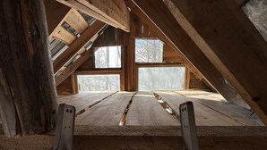 An attic room with wooden beams, a ladder, and large windows. - Streeter Mountain Farm (Rumney)