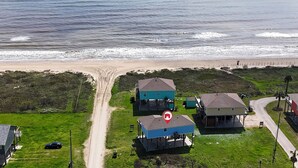 Vue aérienne d’une zone côtière avec des maisons, une plage et un chemin de terre.