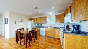 A kitchen with wooden cabinets, a dining table with chairs, a refrigerator, a stove, and a microwave.