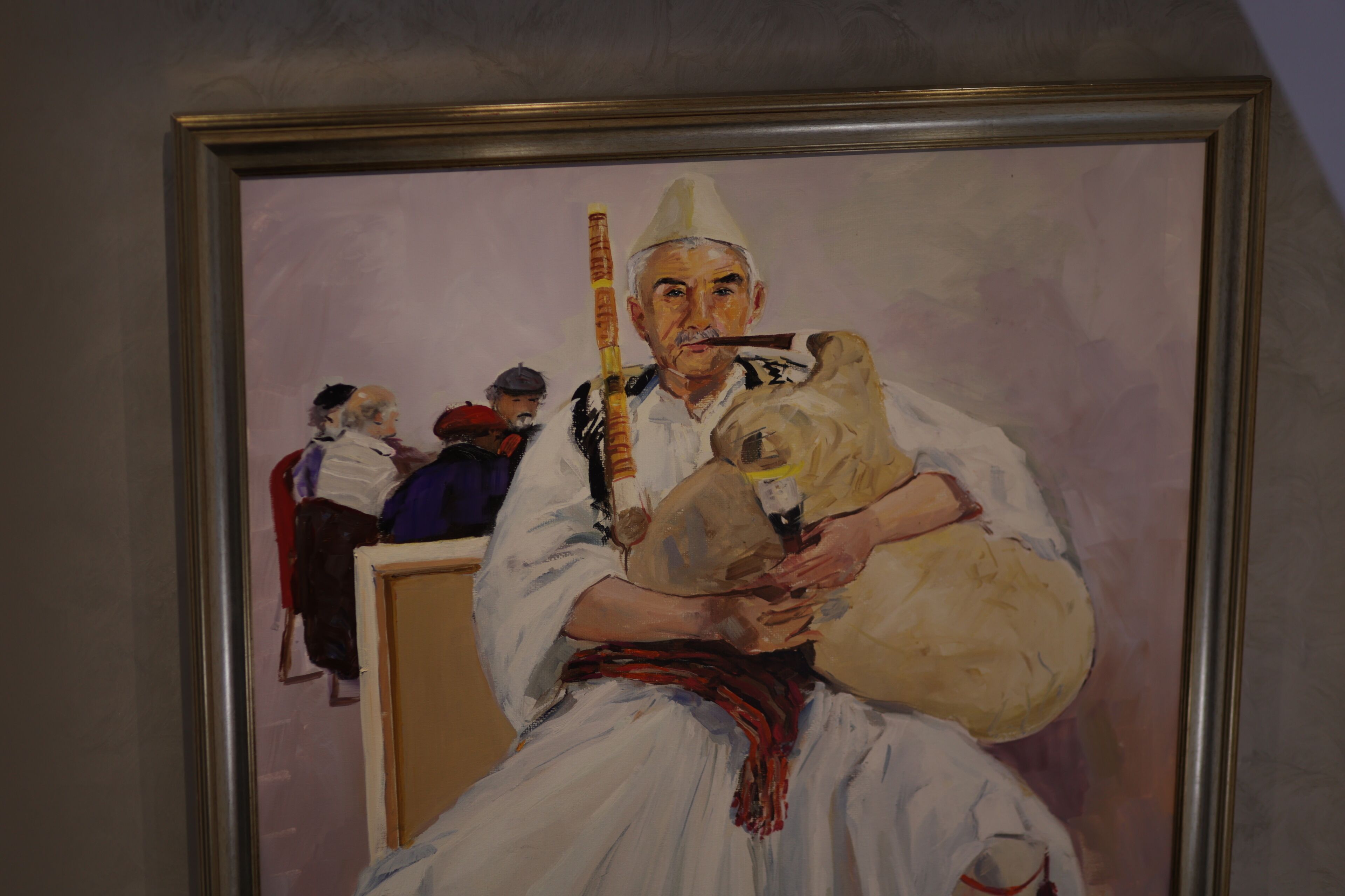 A framed painting of a person holding a child, with a blurred background of other figures.