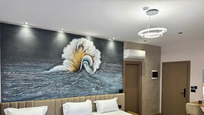 A hotel room with two beds, a large mural of a wave, a modern chandelier, and a wooden floor. - Residence Inn Hotel (Tirana)