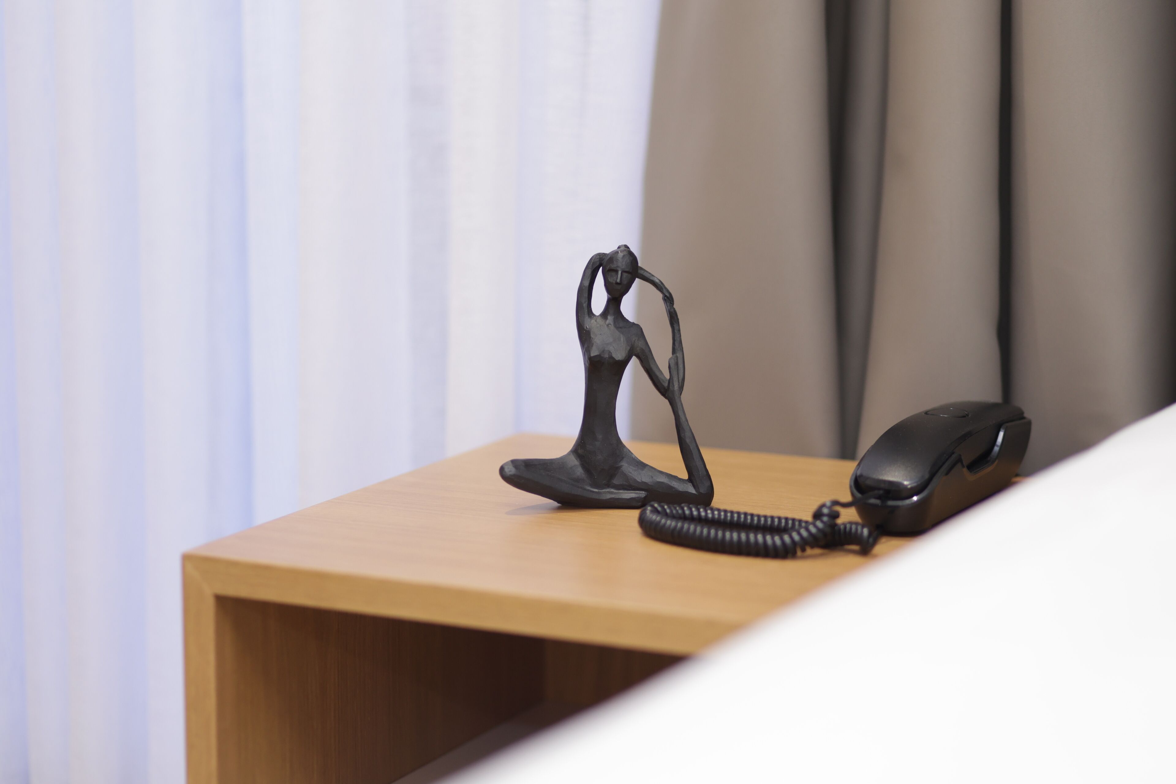 A wooden desk with a black telephone and a black coiled cord.