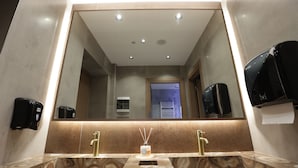 A bathroom with a marble sink, two faucets, a mirror, and a hand dryer. - Residence Inn Hotel (Tirana)