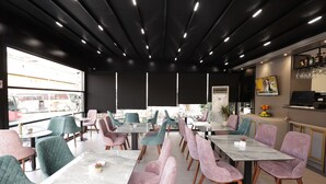 A modern restaurant with a mix of pink and teal chairs, marble tables, and a black ceiling with recessed lighting. - Residence Inn Hotel (Tirana)