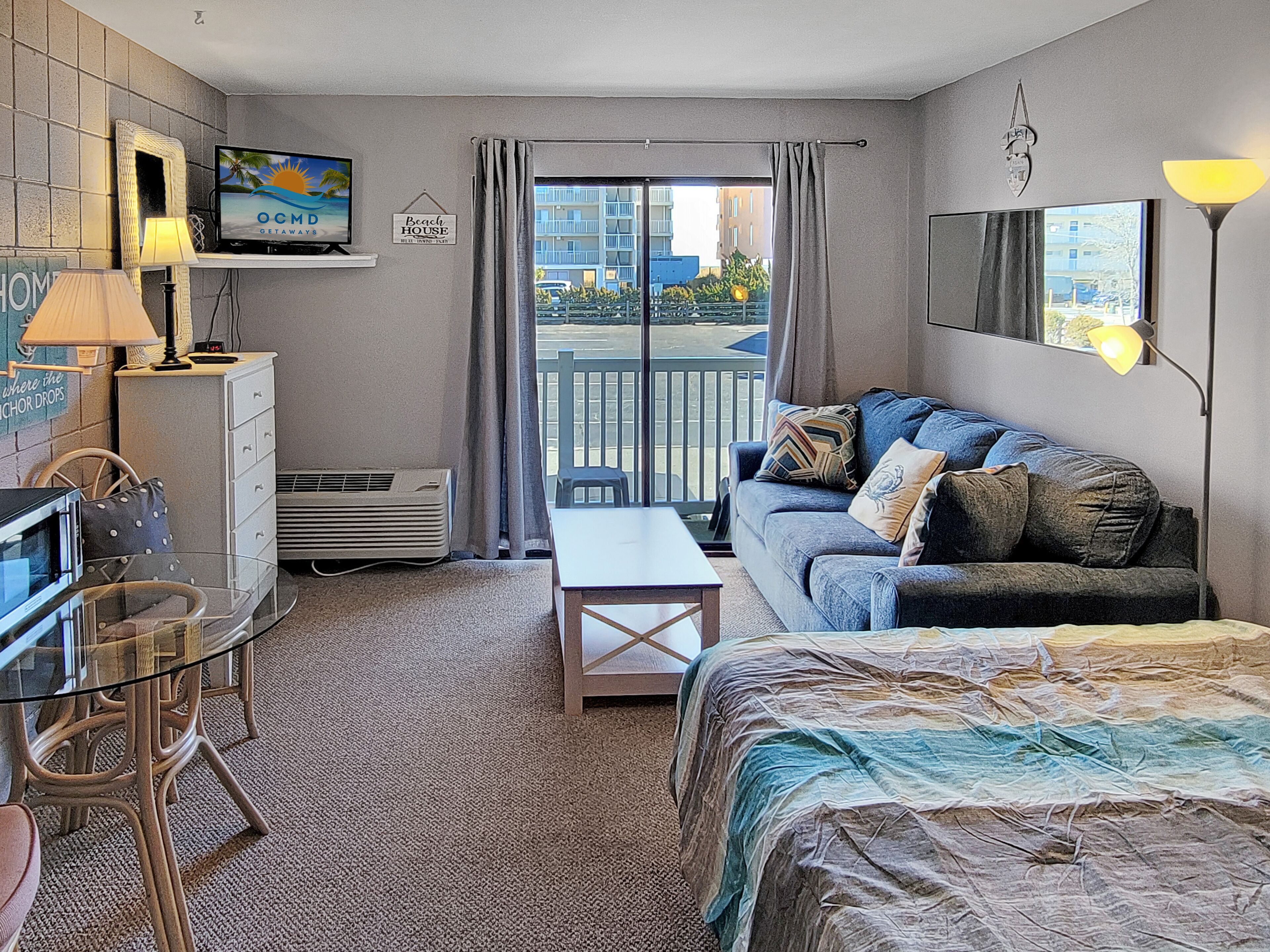Hotelkamer met balkon, bank, bureau, stoel en televisie.