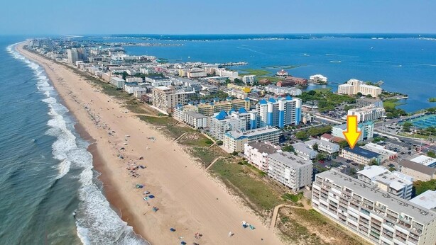 Luftaufnahme einer Küstenstadt mit Strand, Hotels und einem Yachthafen.