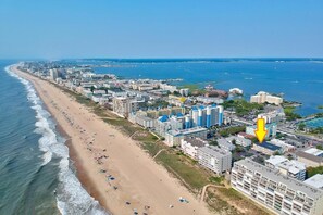 Luchtbeeld van een kuststad met een strand, hotels en een jachthaven.