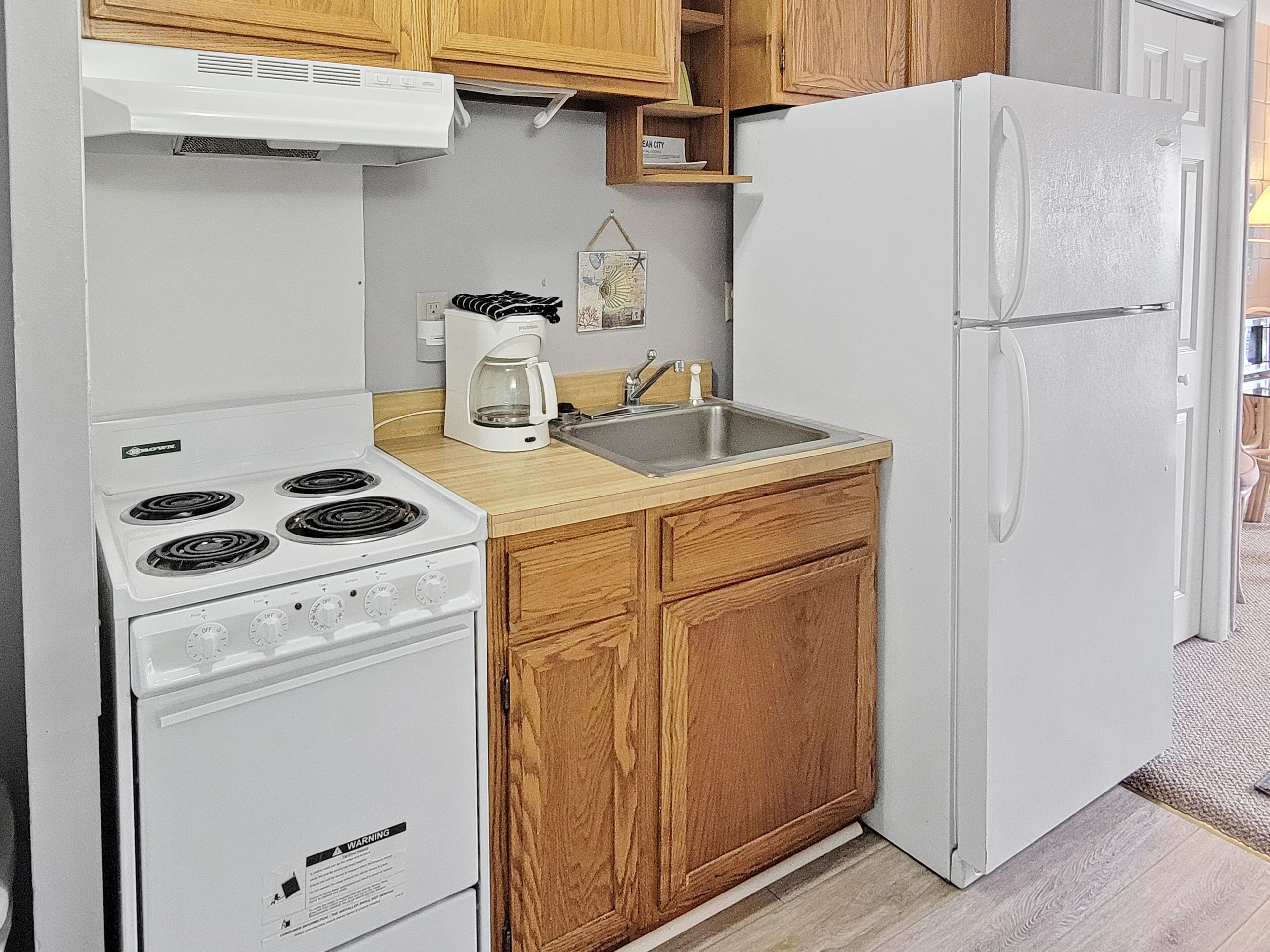 A compact kitchen with a white stove, a sink, and a refrigerator.