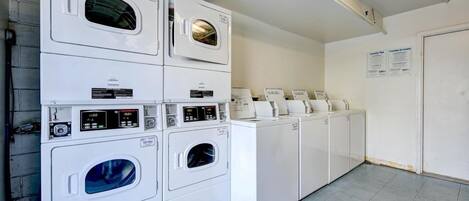A laundry facility with stacked washers and dryers, control panels, and instructional signs.
