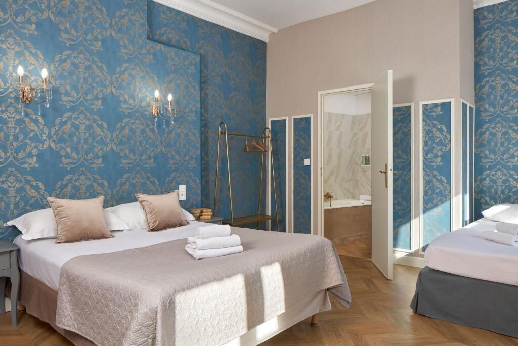 A bedroom with a large bed, a wardrobe, a mirror, and a bathroom with a shower.