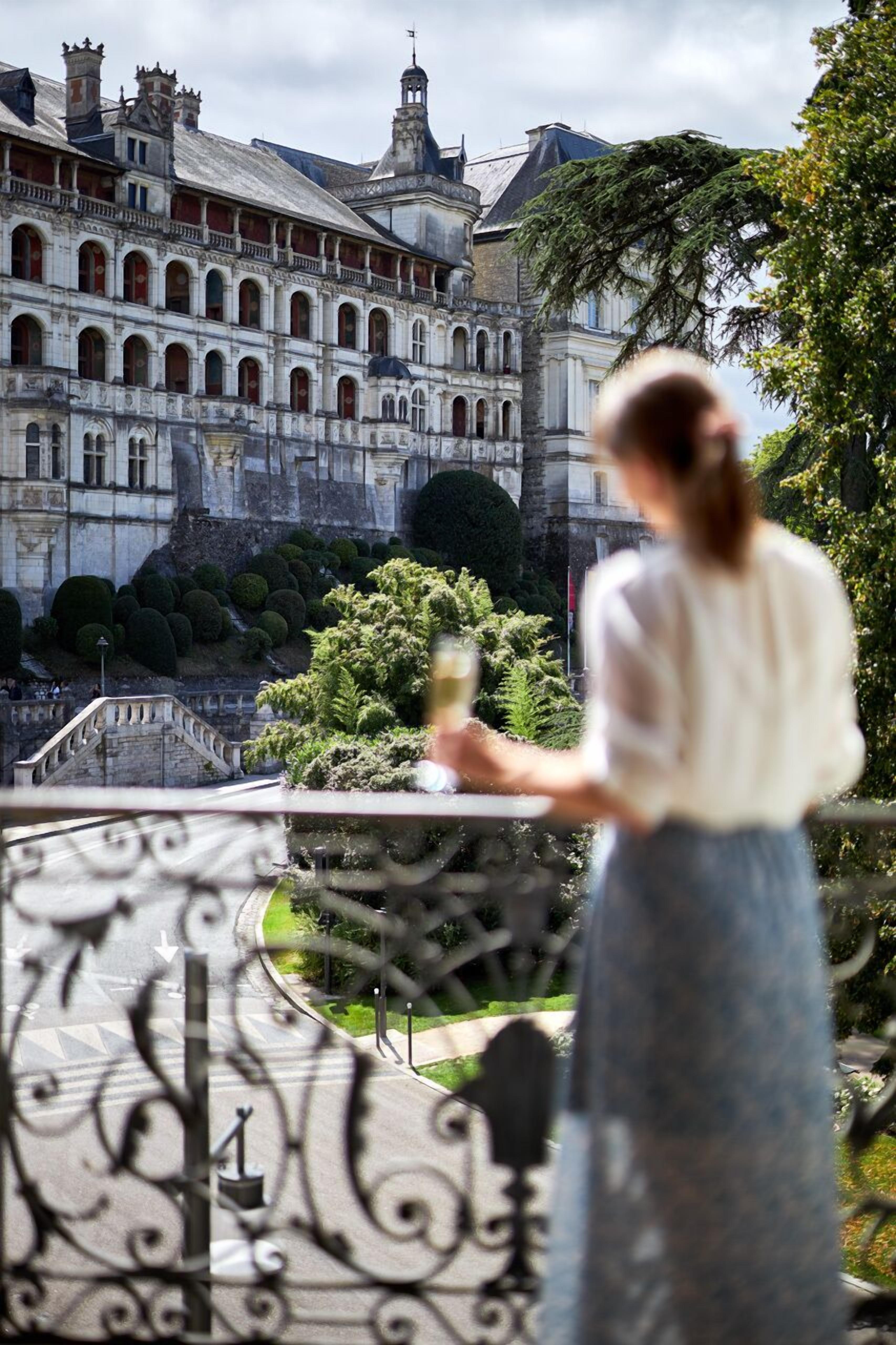 Une personne se tient sur un balcon, d’où l’on peut admirer un bâtiment historique.