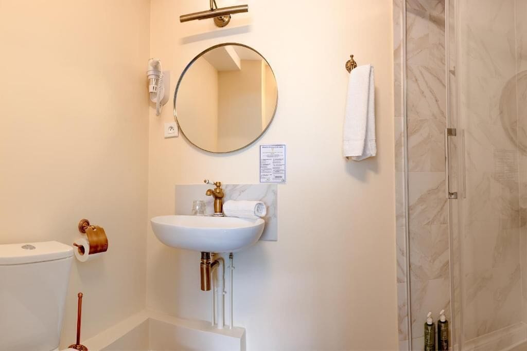 A bathroom with a toilet, sink, mirror, towel, and shower.