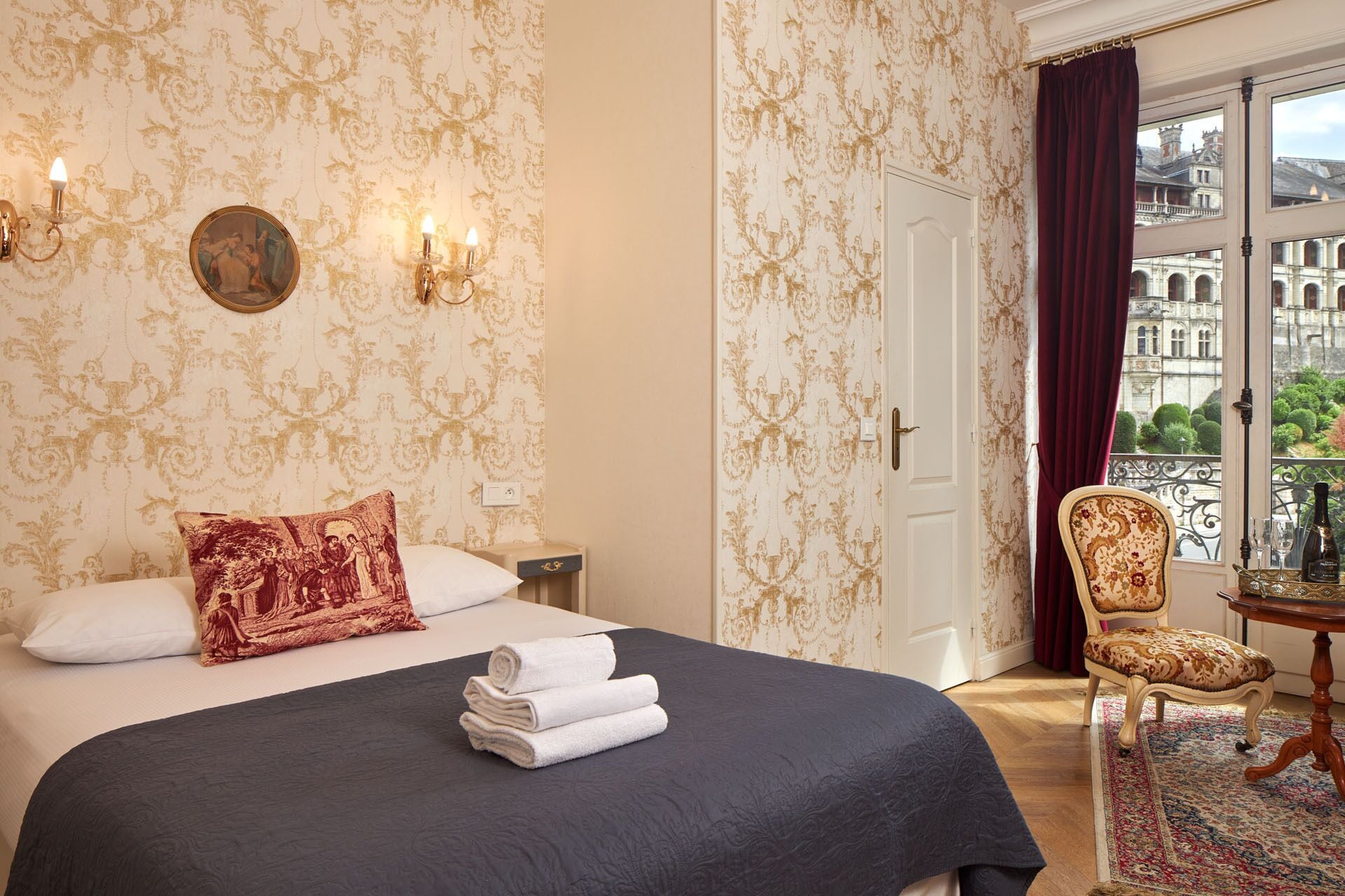 Une chambre d’hôtel avec un lit, une chaise, une table de chevet et une vue sur un immeuble par la fenêtre.