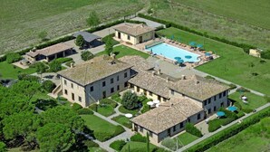 Vue aérienne d’une propriété comprenant plusieurs bâtiments en pierre, une piscine et des jardins bien entretenus.