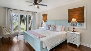 Ein Schlafzimmer mit einem Bett, Nachttischen, einem Sessel und einem Deckenventilator.