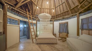 A room with a high ceiling, a bed, a ladder, a chair, and a hanging light fixture. - Villa el Oasis (Santa Marta)