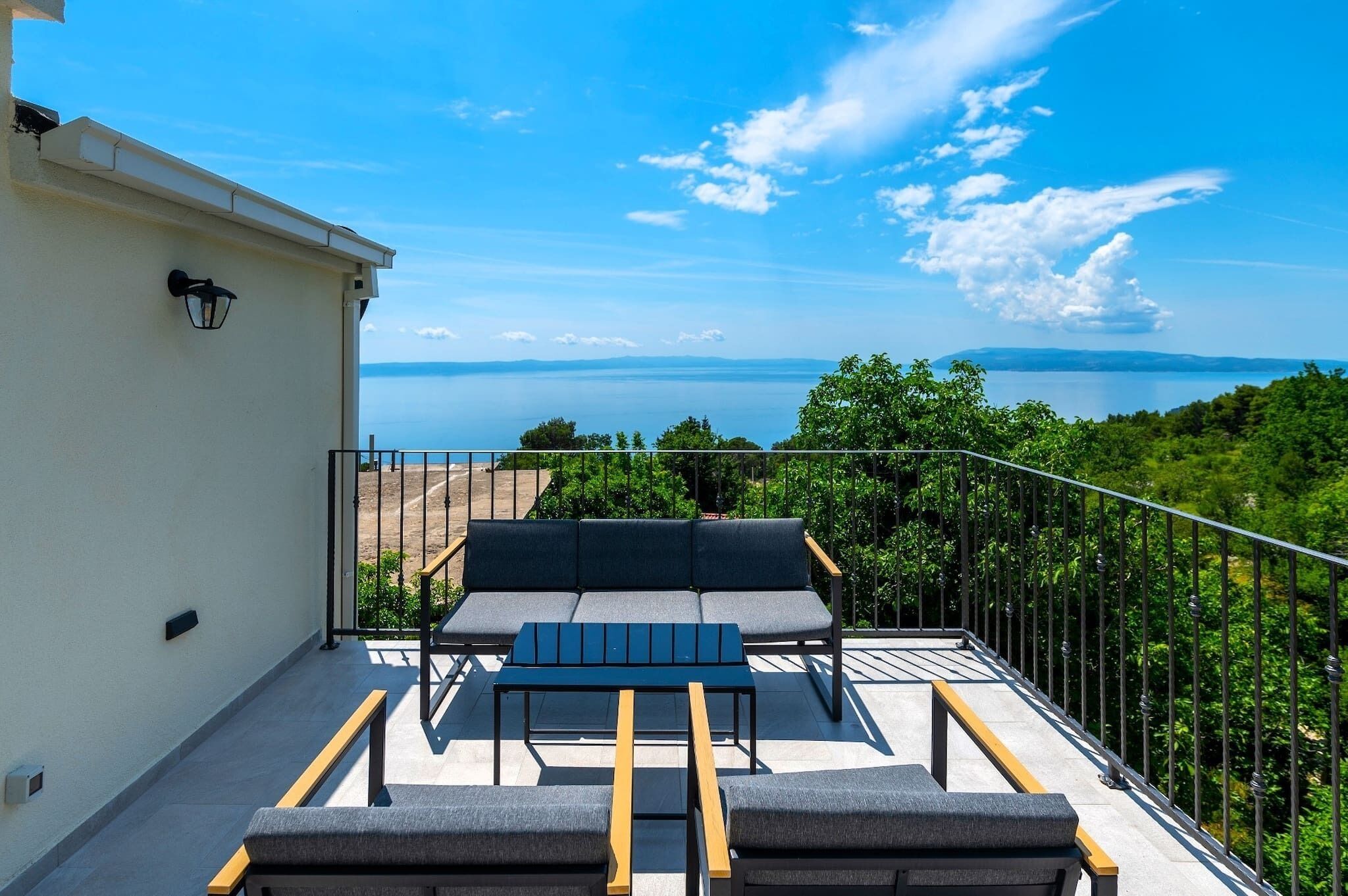 En balkon med sofa, bord og udsigt til vand.