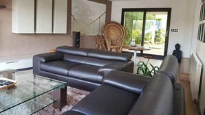 En moderne stue med sofa, glasbord og en fletstol.