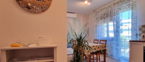 A dining area with a table and chairs, a potted plant, and a wall-mounted picture.