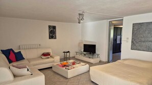 Una sala de estar con un sofá, una mesa de centro, un televisor y un cuadro en la pared.