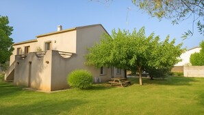 Una casa de un piso con techo plano, un pequeño jardín delantero y una mesa de picnic.