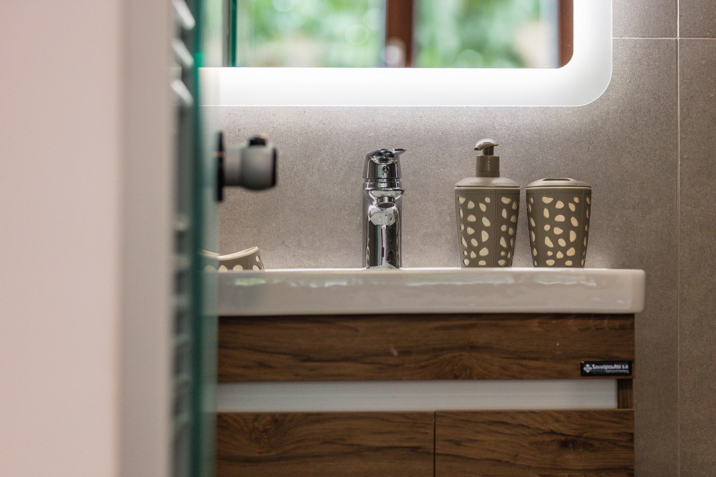 A bathroom with a modern sink, a faucet, and two toiletry containers.