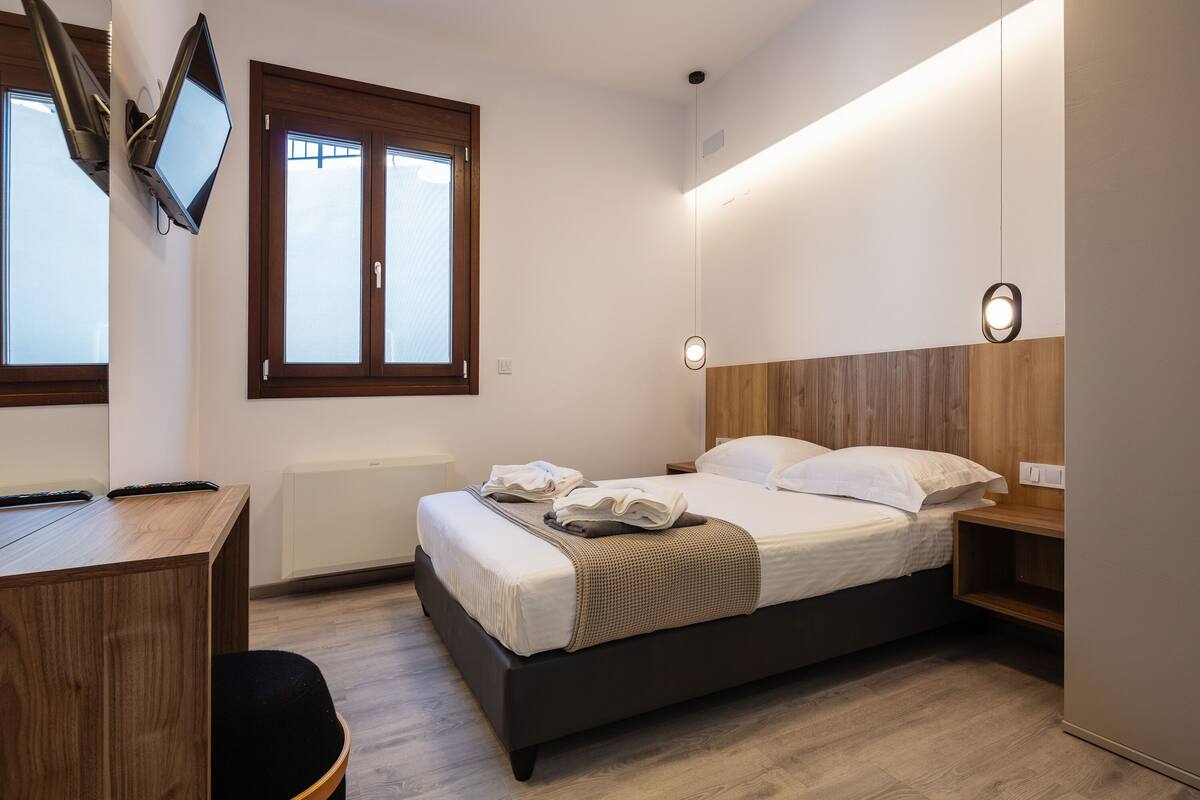 Un dormitorio con cama, mesita de noche y escritorio con silla.