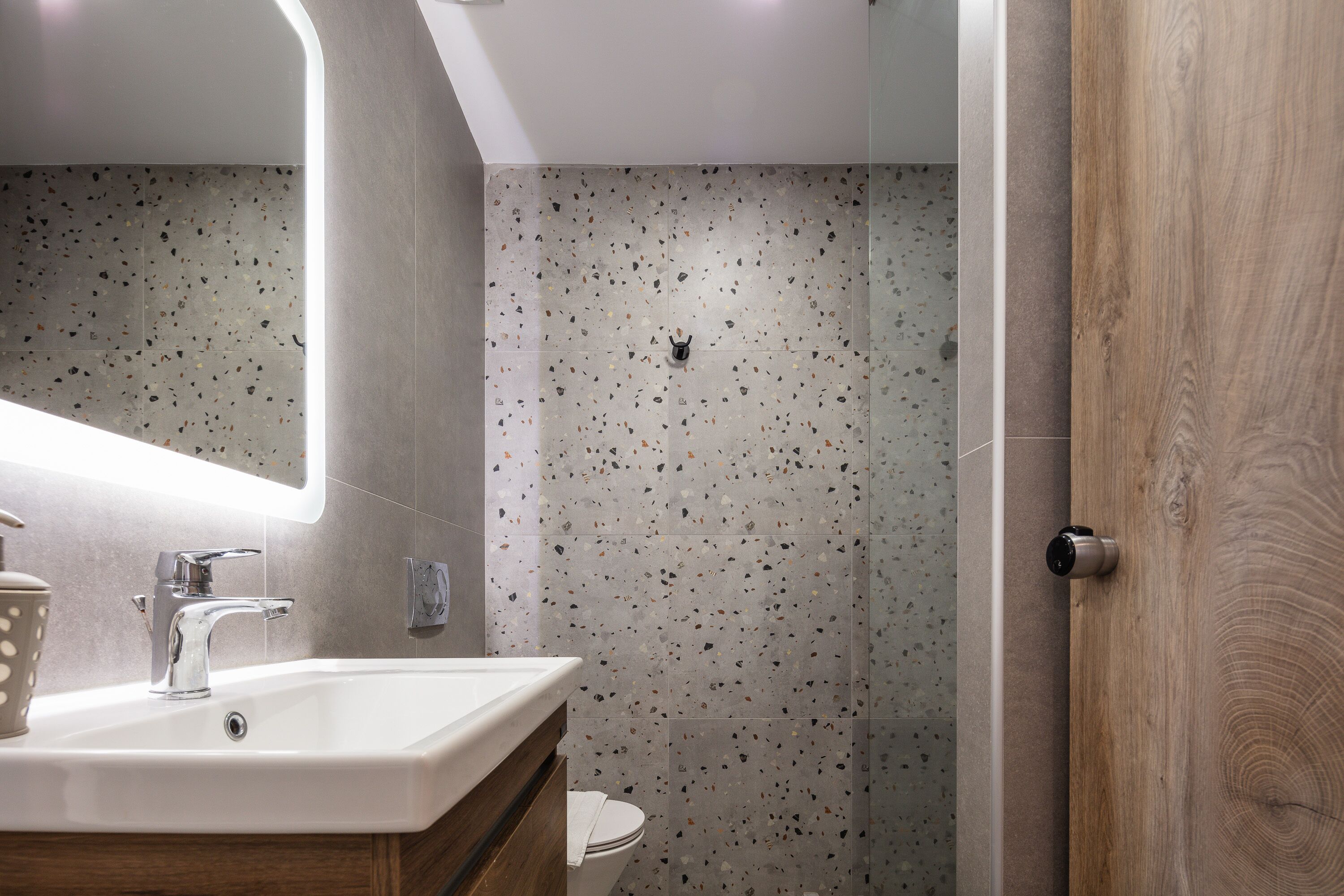A modern bathroom with a white sink, a mirror, and a toilet.
