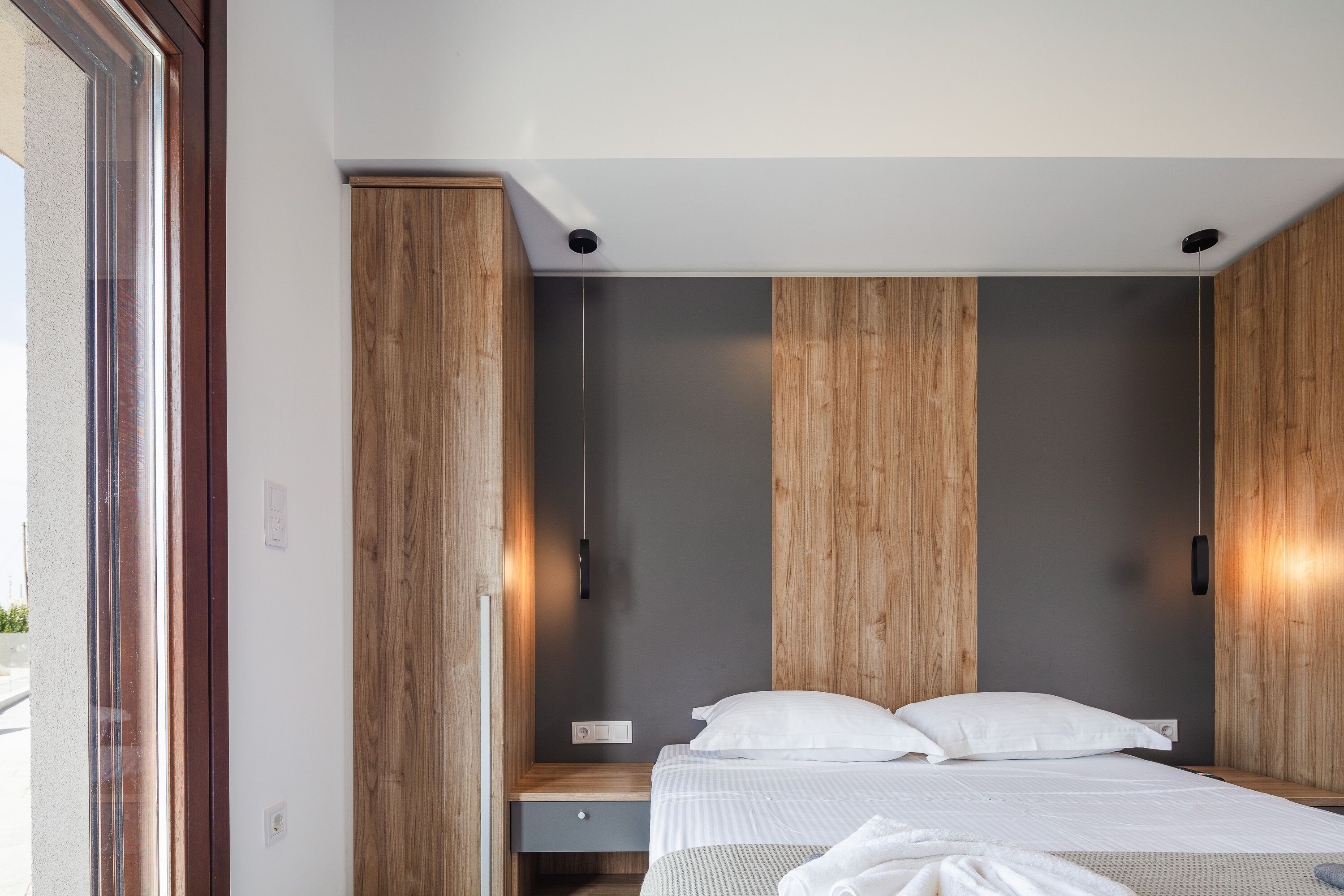 A modern bedroom with a bed, wooden wardrobe, and a nightstand.