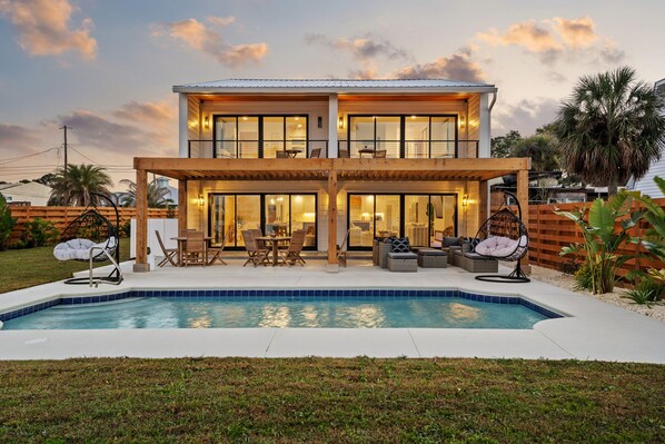 A two-story house with a swimming pool, outdoor seating, and a covered patio area. - Gorgeous Waterfront Luxury Beach House Sleeps 22, Pool, Kayaks (Panama City Beach)