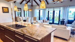 Una cocina moderna con una isla grande, sofás blancos y un comedor.