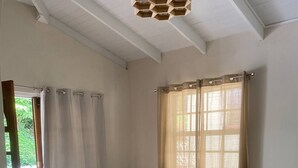 A living room with a grey sofa, a wooden coffee table, and a window with sheer curtains. - 2 bedroom house  (Vieux-fort)
