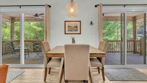 Zona pranzo con tavolo in legno, sedie beige e lampada a sospensione.